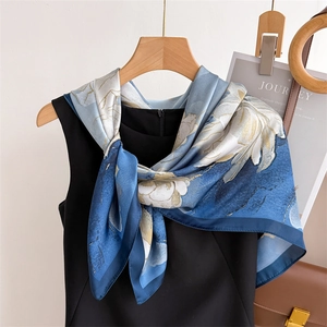 Foulard en soie à imprimé fleuri bleu et blanc avec détails dorés sur tenue noire