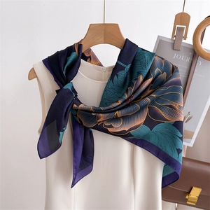Floral silk square scarf with blue and orange lotus print draped on a white top