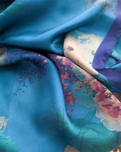 Detail of floral printed silk scarf showing peacock blue satin texture and smooth drape