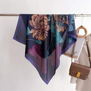 Detail of floral silk-feel scarf with blue base and orange flowers on a metal rack
