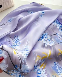 Gros plan du foulard en soie violette avec motifs floraux sur un sac en cuir matelassé blanc