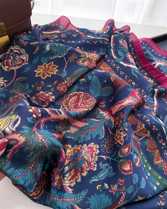 Detailed close-up of bohemian floral silk shawl with bird patterns and magenta edges