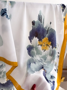 Detail of white silk scarf with blue floral print and yellow borders showing fabric texture