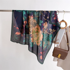 Detail of navy silk-like square scarf featuring large peony print hung near leather bag