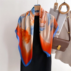 Elegant 90x90cm floral silk scarf with orange and blue patterns on black dress