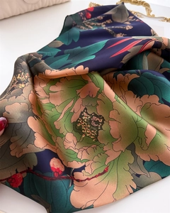Detailed macro view of vibrant floral patterns on smooth silk-like fabric with elegant draping