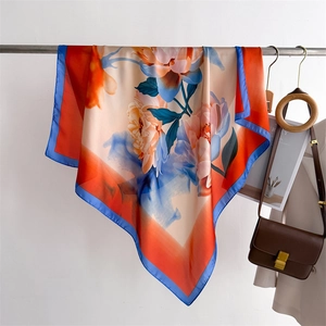 Detail view of large silk-satin scarf with elegant floral patterns and blue borders