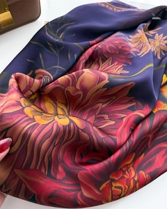Detailed view of floral satin scarf with blue base and vibrant red flower patterns