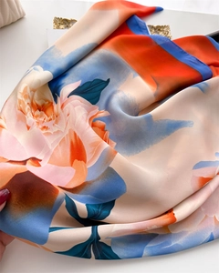 Detailed view of floral silk scarf showing satin texture and vibrant petal print design