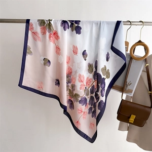 Detailed view of floral silk scarf featuring soft leaf prints and navy blue contrast borders
