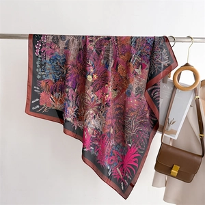 Detailed shot of large floral satin scarf with tropical print and elegant brown hem