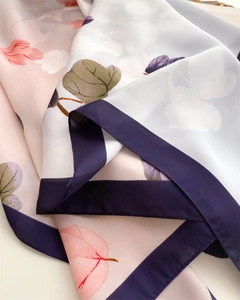 Detailed view of leaf print silk scarf with gradient pink blue tones and purple border