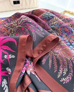 Detailed macro view of vibrant tropical floral silk scarf with premium satin edge texture
