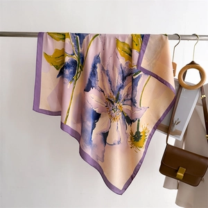 Close-up of elegant floral silk scarf draped with a vintage brown crossbody bag