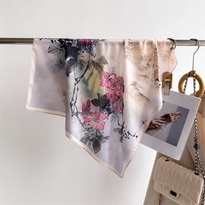 Detail of a silk scarf with ink flower prints hanging on a stainless steel bar
