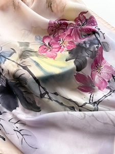 Detail view of smooth silk scarf with elegant pink floral print and flowing texture