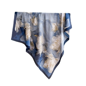 Foulard en soie bleu avec motifs floraux beige et bordure bleu marine sur fond blanc