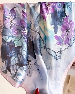 Close-up of elegant floral print on blue silk satin scarf with pink hemmed edges