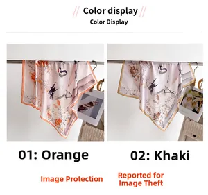 Dettaglio di un foulard in finta seta con stampa di gru e fiori in arancio e kaki