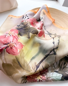 Detail of silk scarf with floral ink painting and orange hand-rolled edges on wood tray