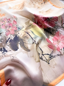 Close-up of silk scarf showing floral prints and vibrant orange rolled edges