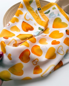 Dettaglio di un foulard in seta con cuori sfumati gialli e bordi rifiniti di alta qualità