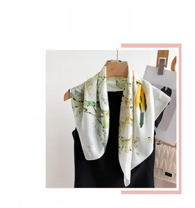 Detail of silk-like scarf with vibrant yellow birds and green floral pattern