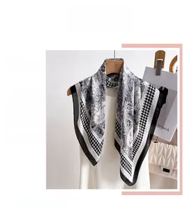 Close-up of houndstooth and paisley print silk scarf hanging on a wooden hanger