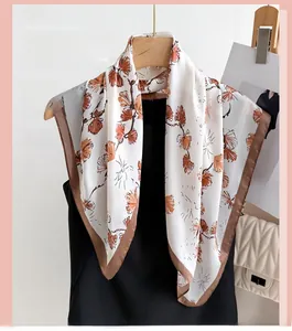 Detail of silk-like floral square scarf with brown border hanging on a wooden hanger