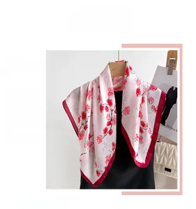 Detail of silk-like pink scarf with floral print and deep red contrast stitched edges