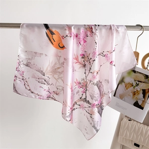 Close-up of lightweight satin scarf featuring a floral and bird print with rolled edges