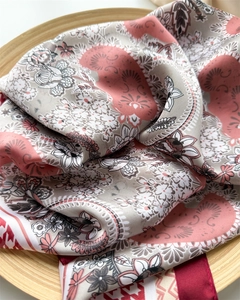 Detail of silk-like scarf featuring vintage floral and paisley print on a wooden tray