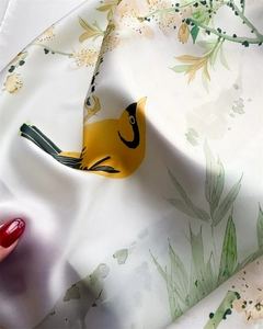 Detail of satin scarf fabric with vibrant bird and floral print featuring elegant draping