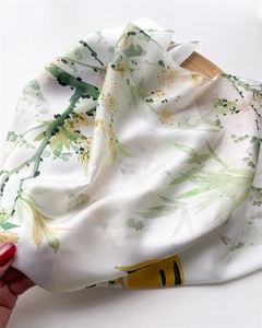Detail of silk-like scarf featuring watercolor floral prints on a rustic wooden base