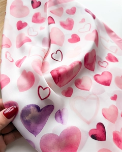 Dettaglio di un foulard di seta bianco con cuori acquerello e trama di tessuto morbido