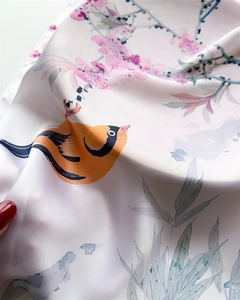 Detailed view of silk square scarf featuring vibrant floral and bird print textures