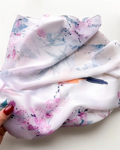 Close-up of silk-like scarf featuring pink floral blossoms and blue bird prints