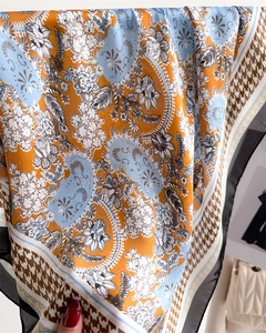 Close-up of orange and blue paisley silk scarf with houndstooth edge and luxury gloss