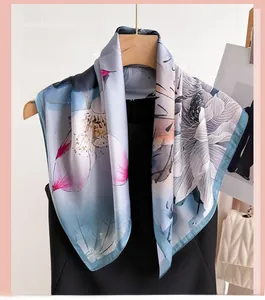 Détail d'un foulard carré en satin soyeux avec imprimé floral lotus sur fond bleu clair