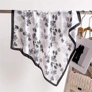 Detail showing high-quality silk square scarf with elegant black and white floral prints