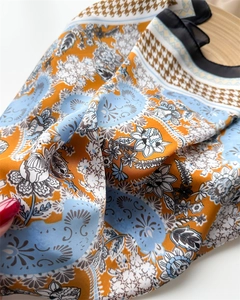 Macro detail of high-quality satin scarf with orange floral and paisley patterns
