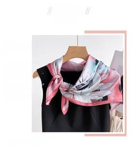 Détail d'un foulard élégant en soie à motif floral rose sur un cintre pour femme