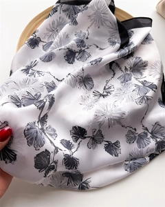 Close-up of silk-feel square scarf with floral print and black border on a tray