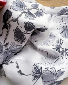Macro view of soft faux silk scarf featuring delicate black floral sketches on white fabric