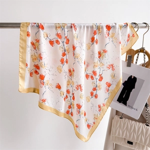 Detail of floral silk scarf ivory white fabric with orange print and golden satin border