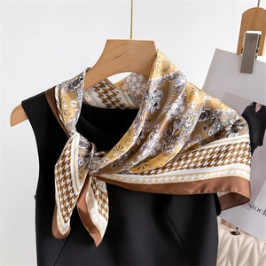 Close-up of silk neckerchief with houndstooth and floral prints on a wooden hanger