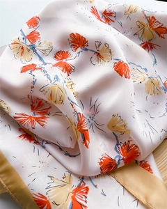 Close-up of elegant floral silk scarf with orange and blue brushstrokes on cream fabric