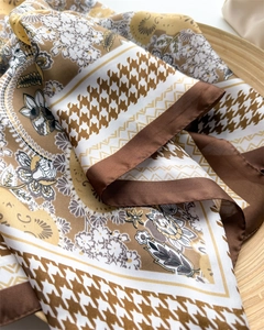 Detailed view of houndstooth silk scarf with paisley patterns in brown and yellow