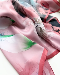 Gros plan d'un foulard en soie rose à fleurs montrant la texture et les bords roulés