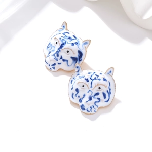 Close-up of blue and white enamel tiger earrings with gold trim in porcelain style